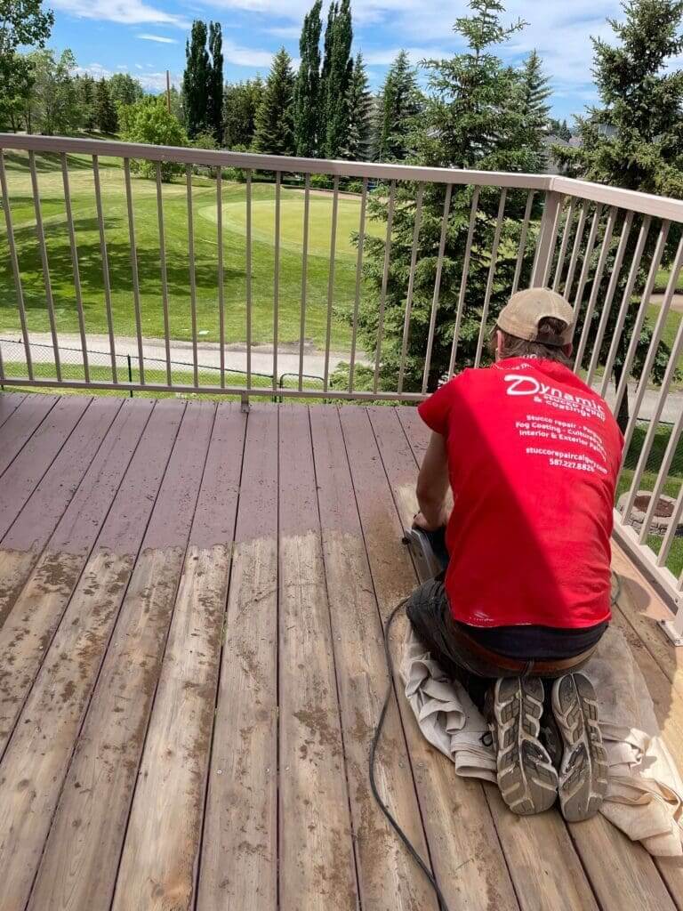 Dynamic team member sanding refinished deck for a new coat of solid stain